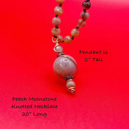 Peach Moonstone knotted necklace with a 2-inch pendant on a red background