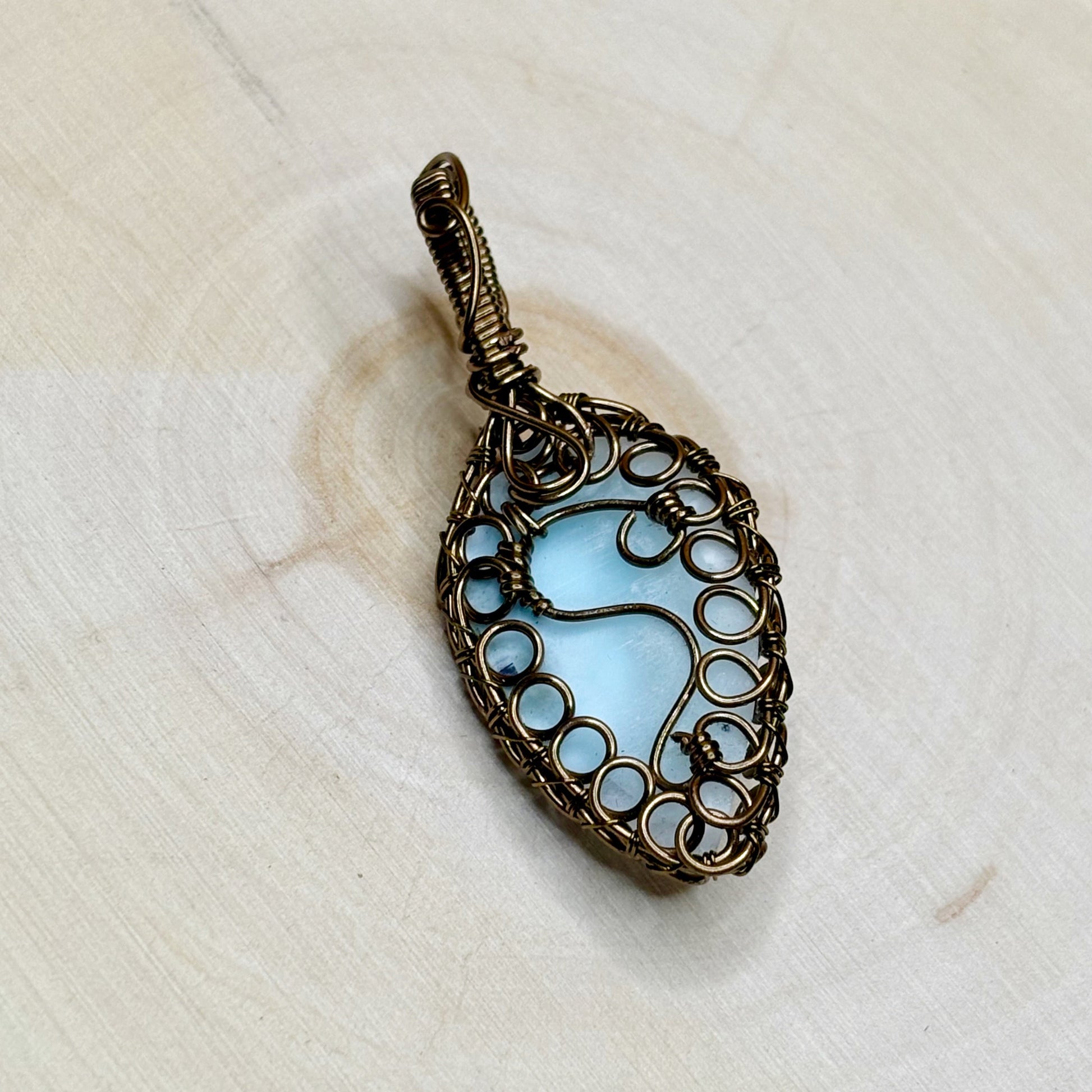 Decorative pendant with blue stone on a white wooden background