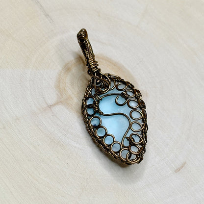 Decorative pendant with blue stone on a white wooden background