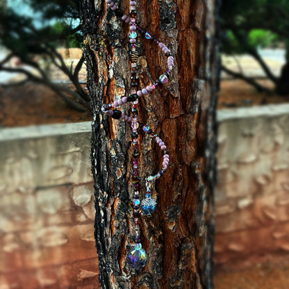 Beaded sun catcher hanging on a tree trunk with a blurred natural background