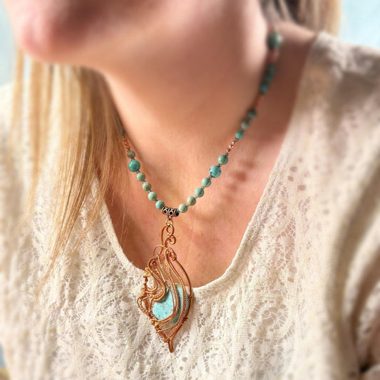 Turquoise beaded necklace with a decorative pendant worn by a person in a white lace top.