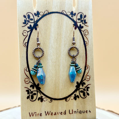 Pair of earrings with blue teardrop-shaped beads on a decorative card with 'Wire Weaved Uniques' branding.