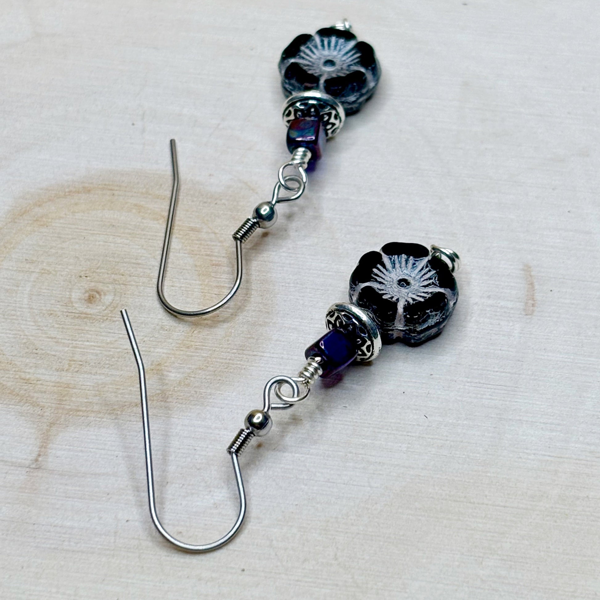 Pair of black floral beaded earrings on a light wooden surface