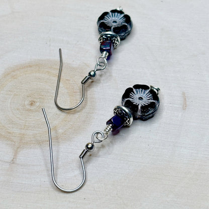 Pair of black floral beaded earrings on a light wooden surface