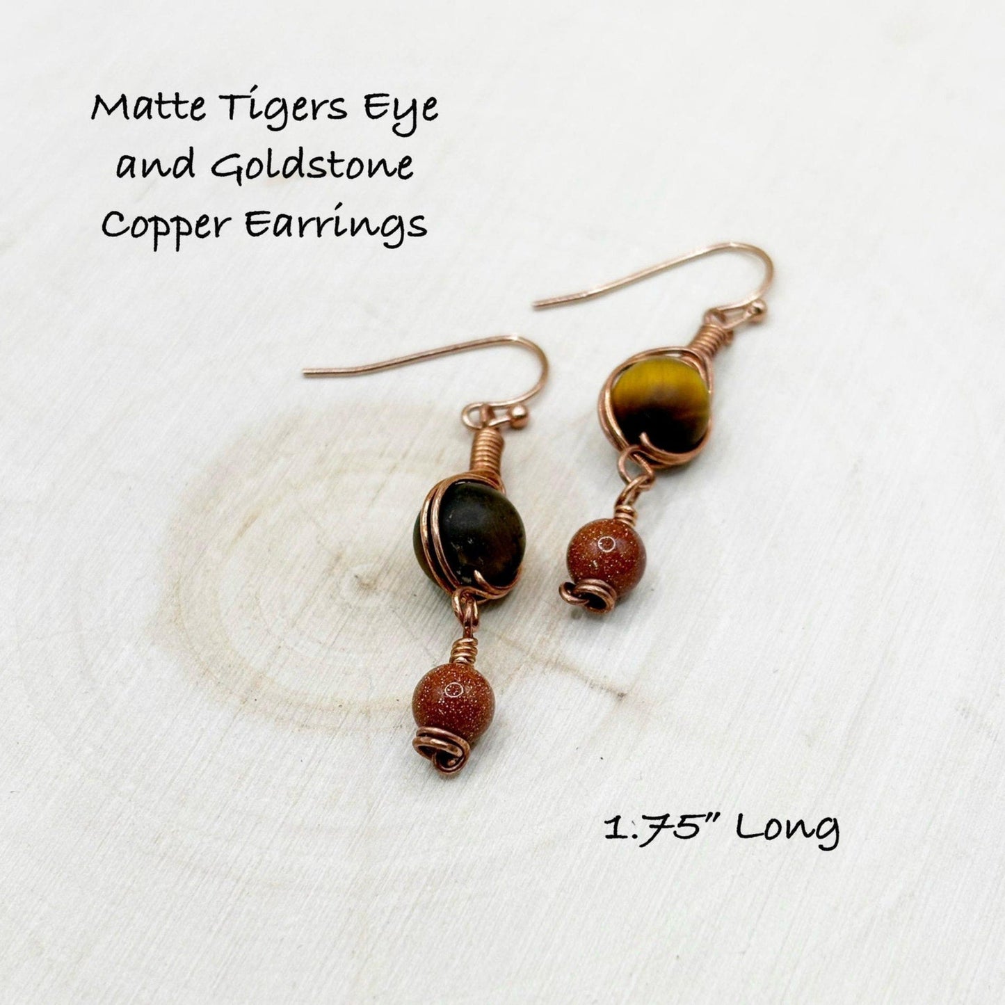 Matte Tigers Eye and Goldstone Copper Earrings on a textured white background