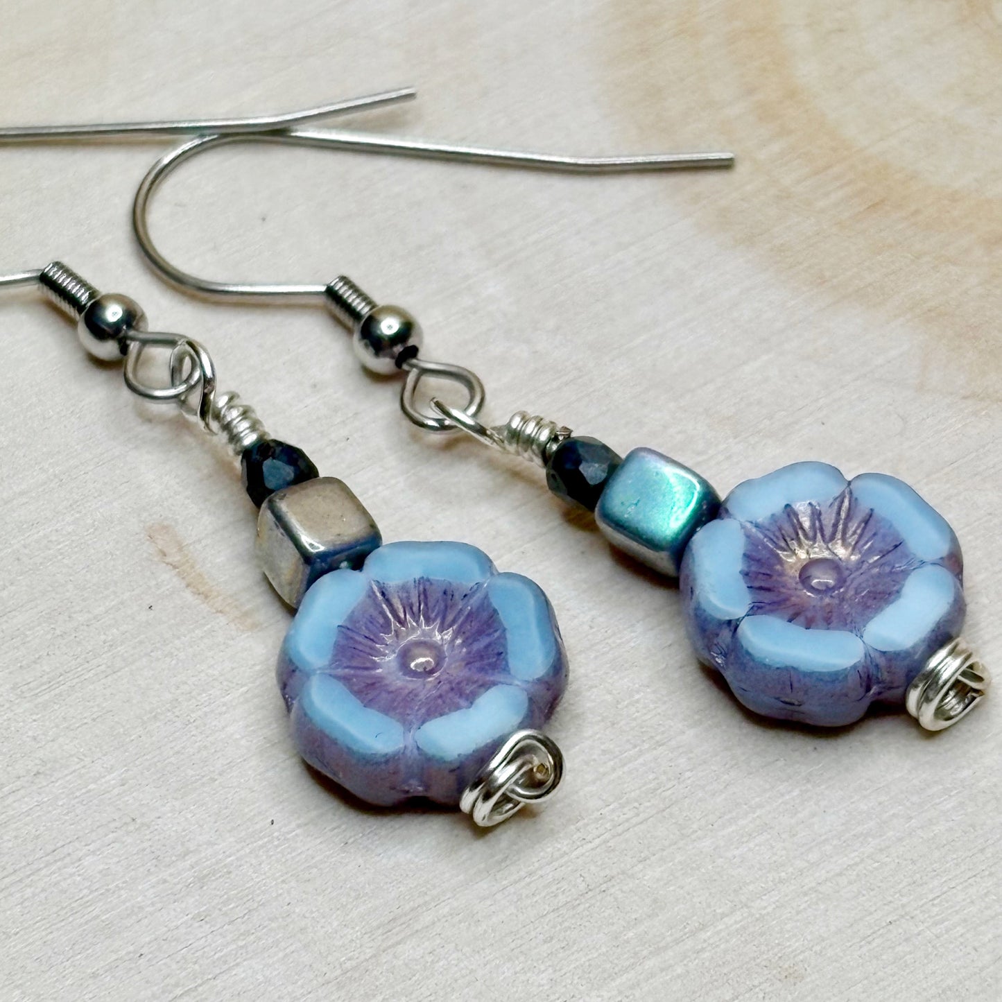 Flower-shaped earrings with blue and purple flowers on a light background