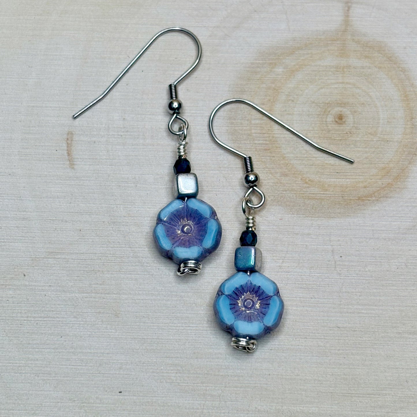 Pair of blue floral beaded earrings on a wooden surface