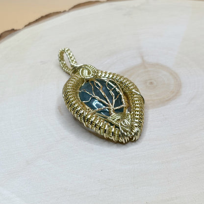 Gold pendant with tree design on a wooden background