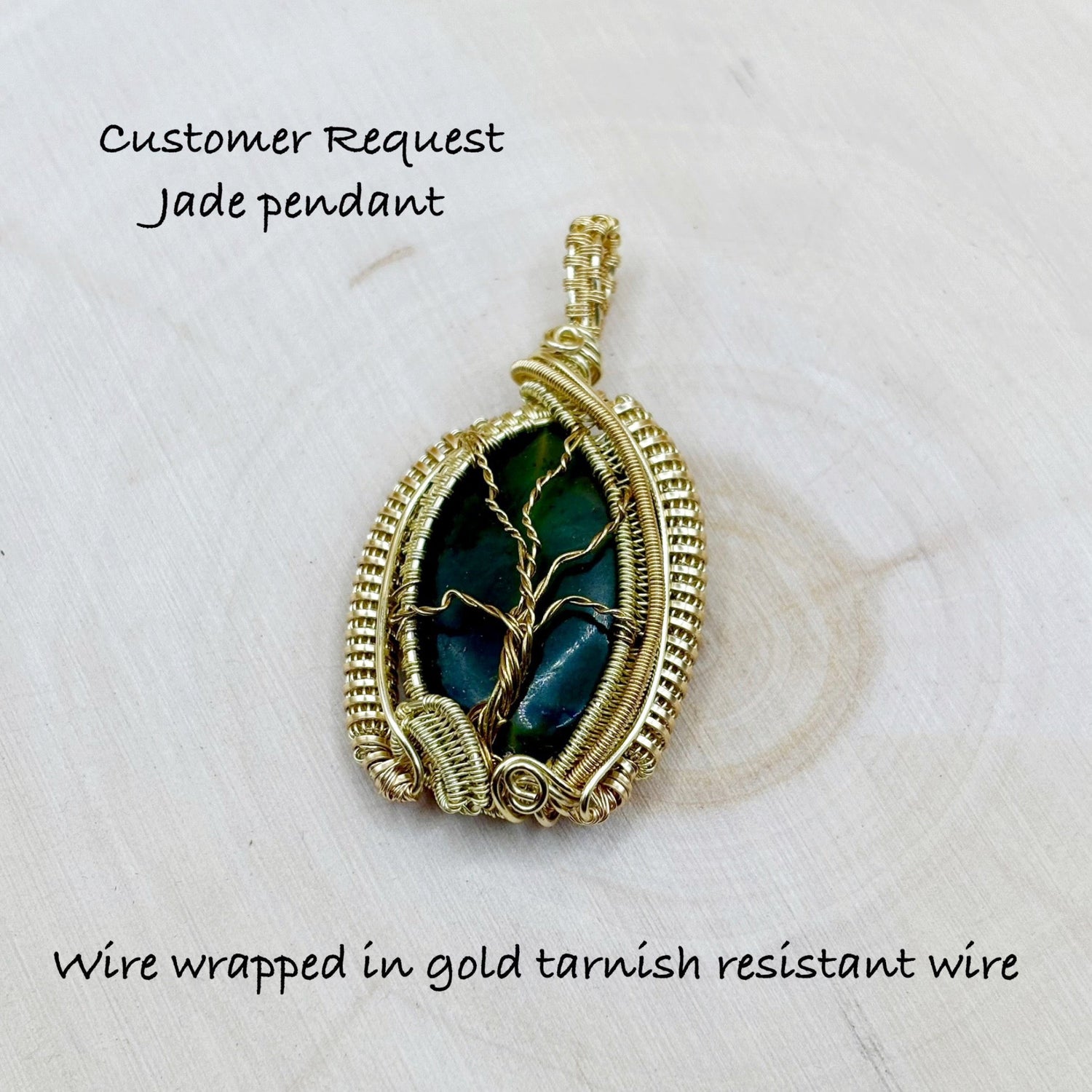Jade pendant wire wrapped in gold tarnish resistant wire on a light background