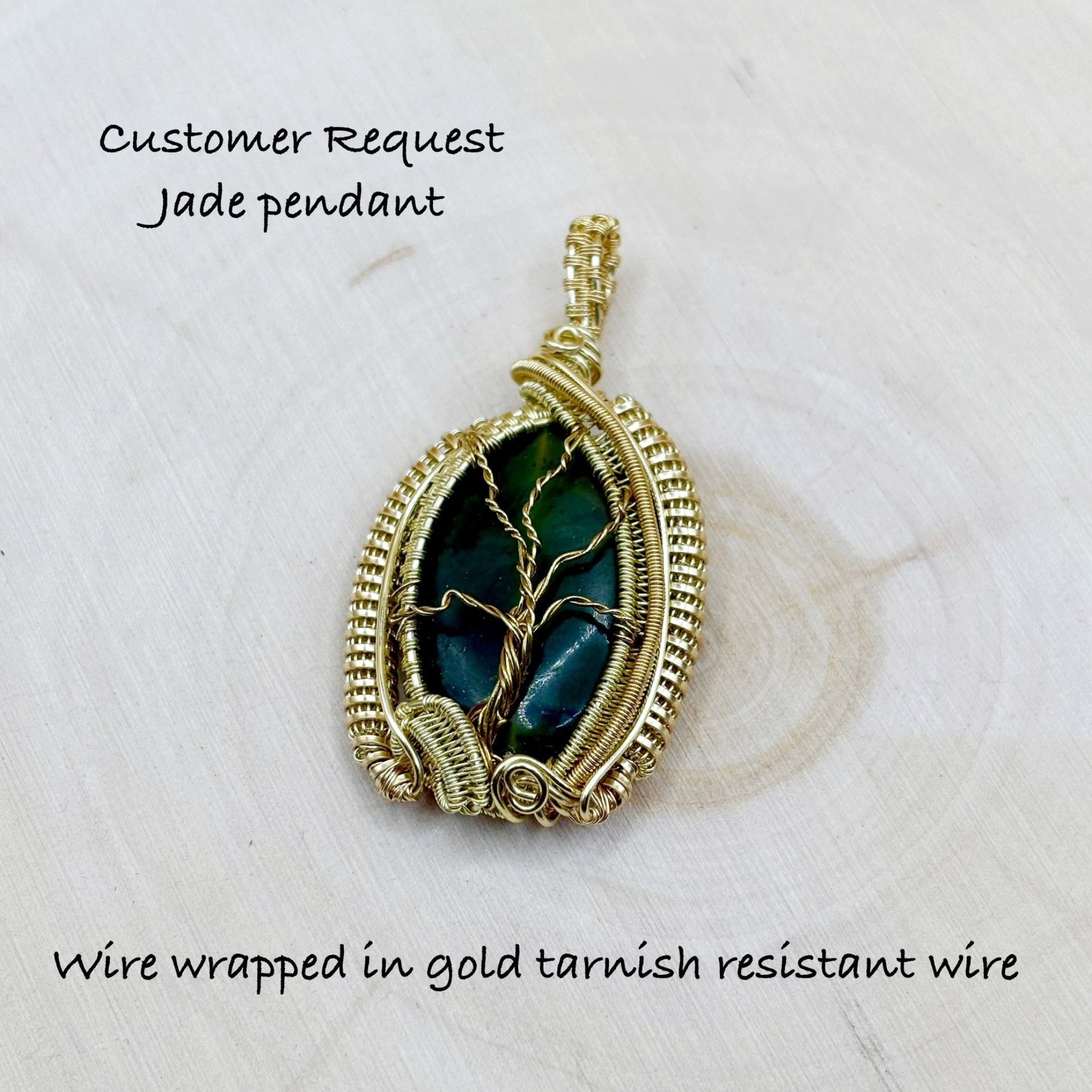Jade pendant wire wrapped in gold tarnish resistant wire on a light background