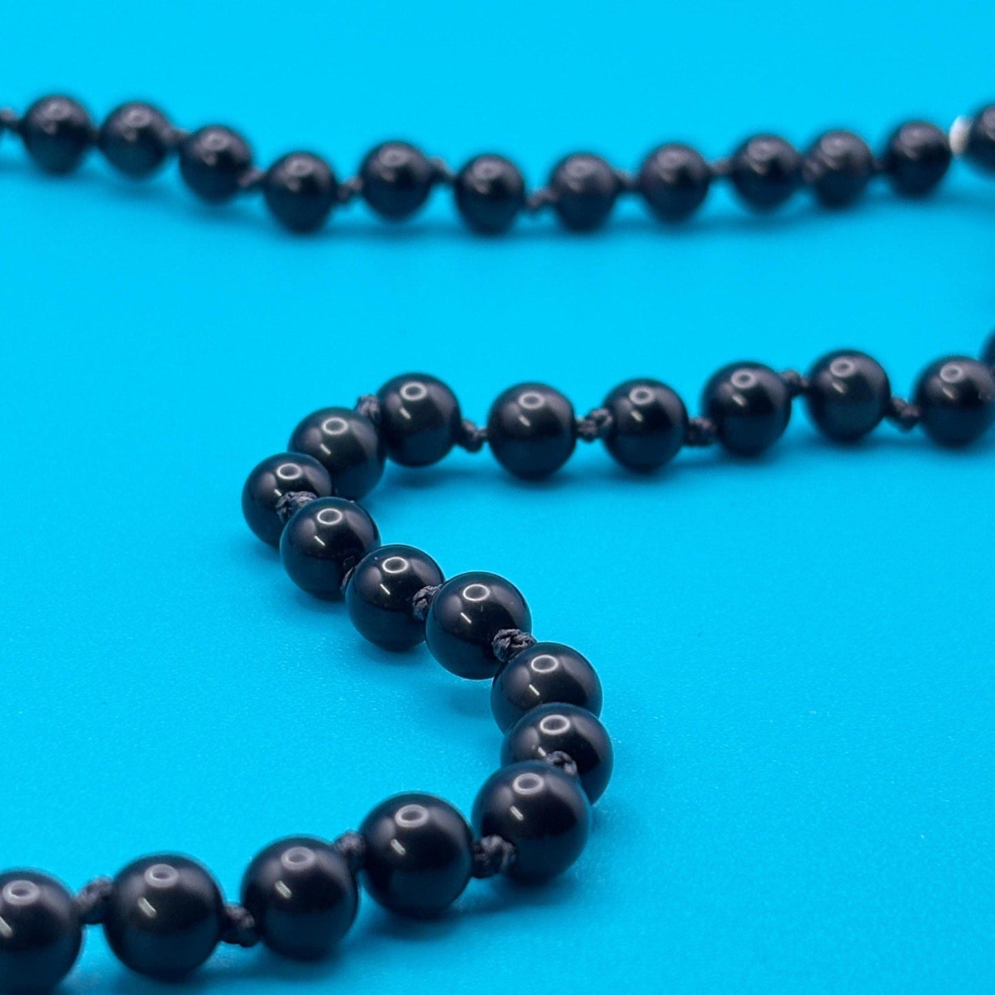 Black beaded necklace on a blue background