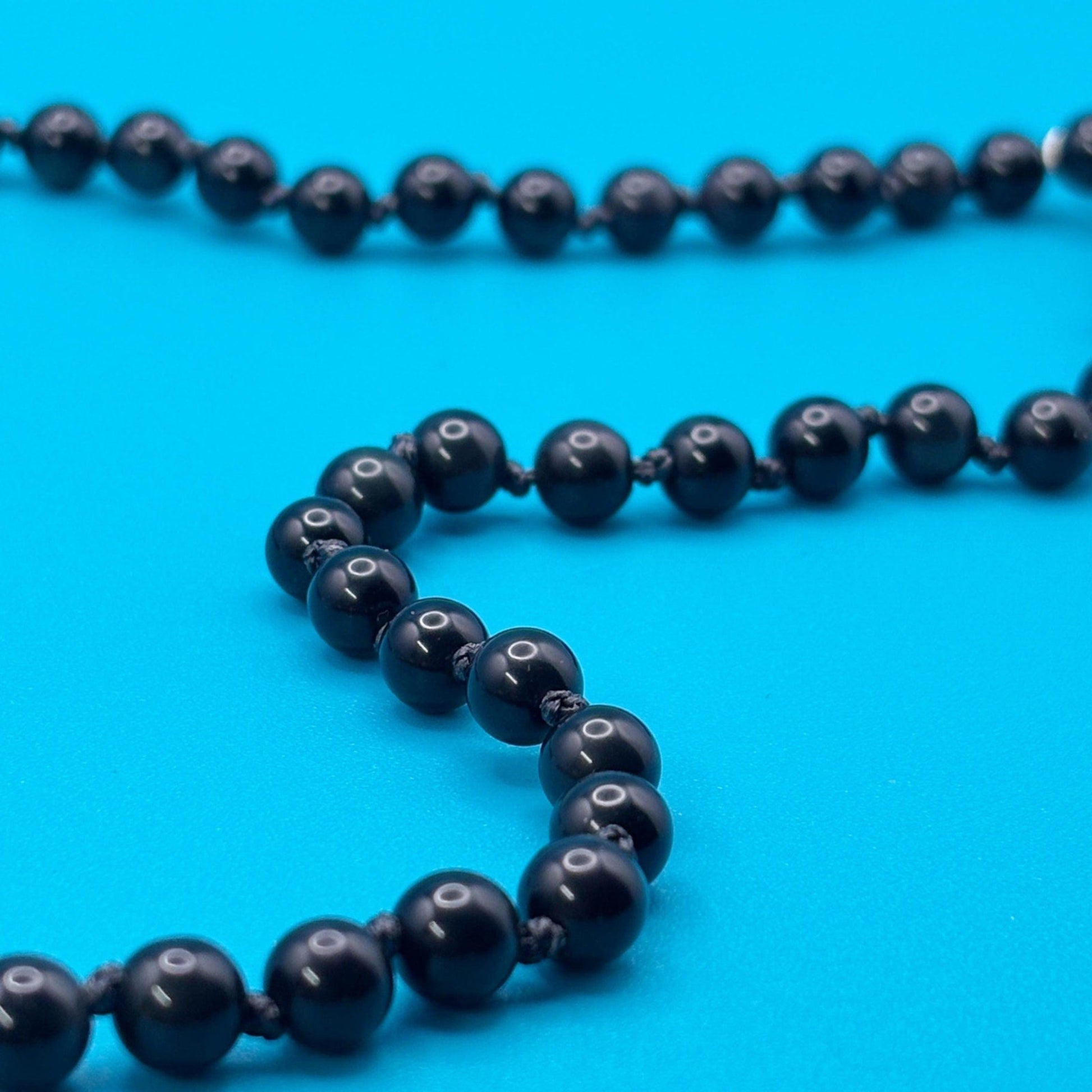 Black beaded necklace on a blue background