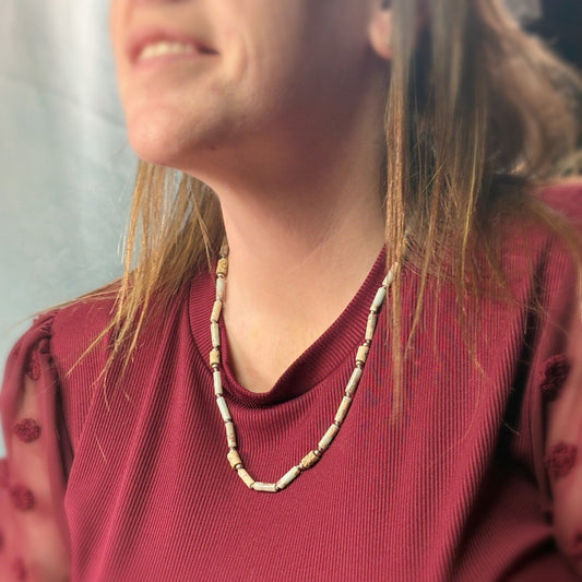 Person wearing a red sweater and a beaded necklace with a blurred background