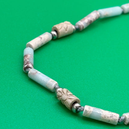 Necklace with light blue and beige beads on a green background
