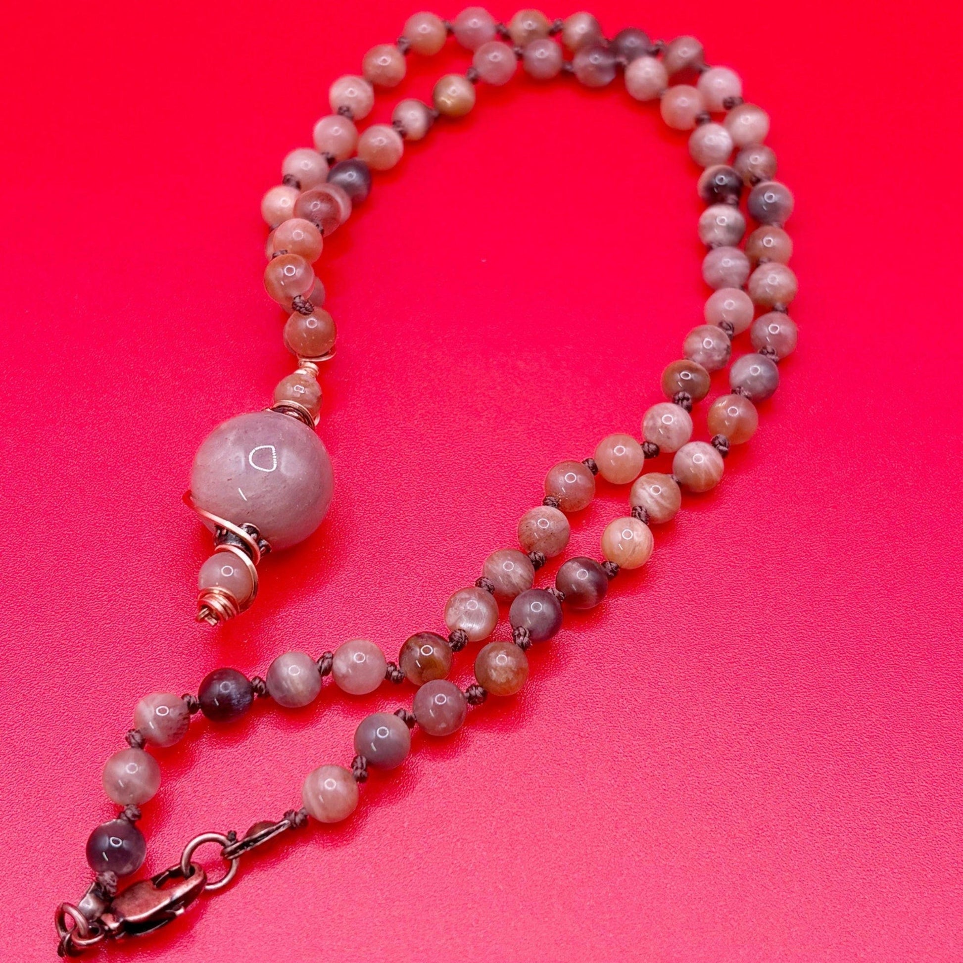 Beaded necklace with a pink and brown color scheme on a red background