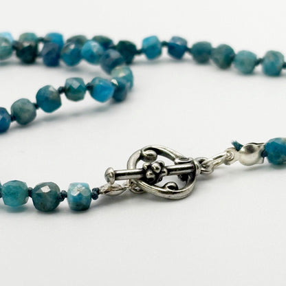 Blue beaded necklace with a silver clasp on a white background