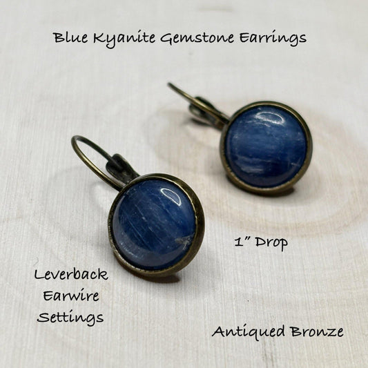 Blue kyanite gemstone earrings with antiqued bronze settings on a white wooden background.-p