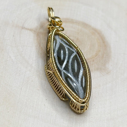 Gold-framed pendant with intricate design on a beige fabric background
