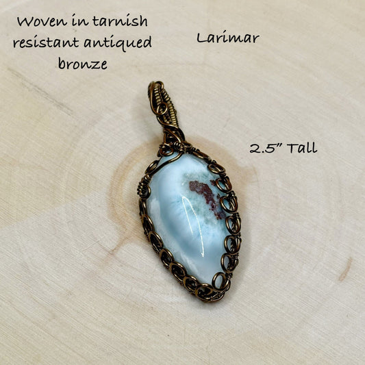 Larimar pendant with bronze wire wrapping on a beige background