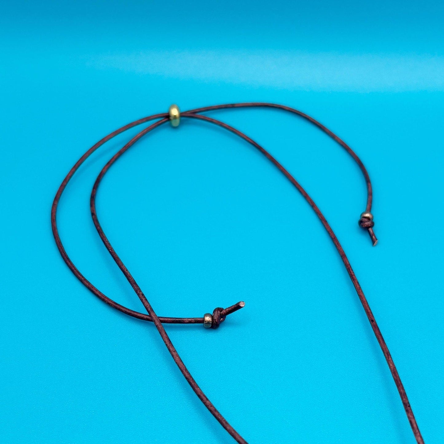 Black cord necklace with gold clasp on a blue background