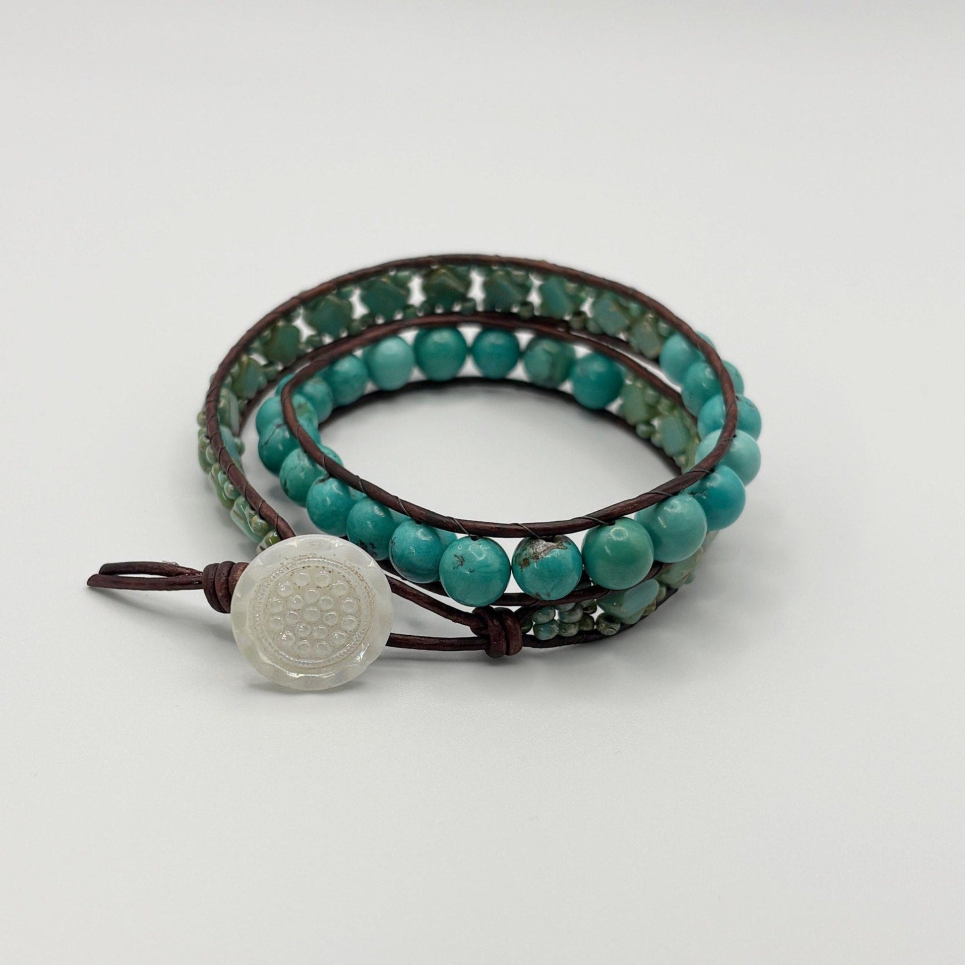 Turquoise beaded bracelet with a white stone on a light gray background