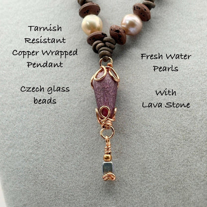 Necklace with copper wrapped pendant, fresh water pearls, and lava stone on a gray background