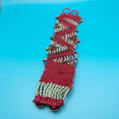 Beaded bracelet with red and copper pattern on a blue background