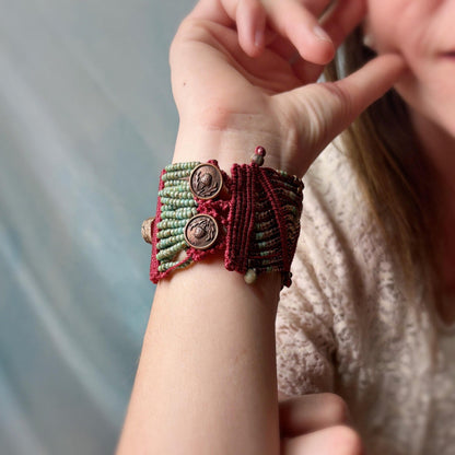 Close-up of a hand wearing a red and green macrame bracelet with buttons.