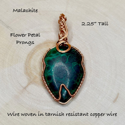 Malachite pendant with flower petal prongs on a textured surface