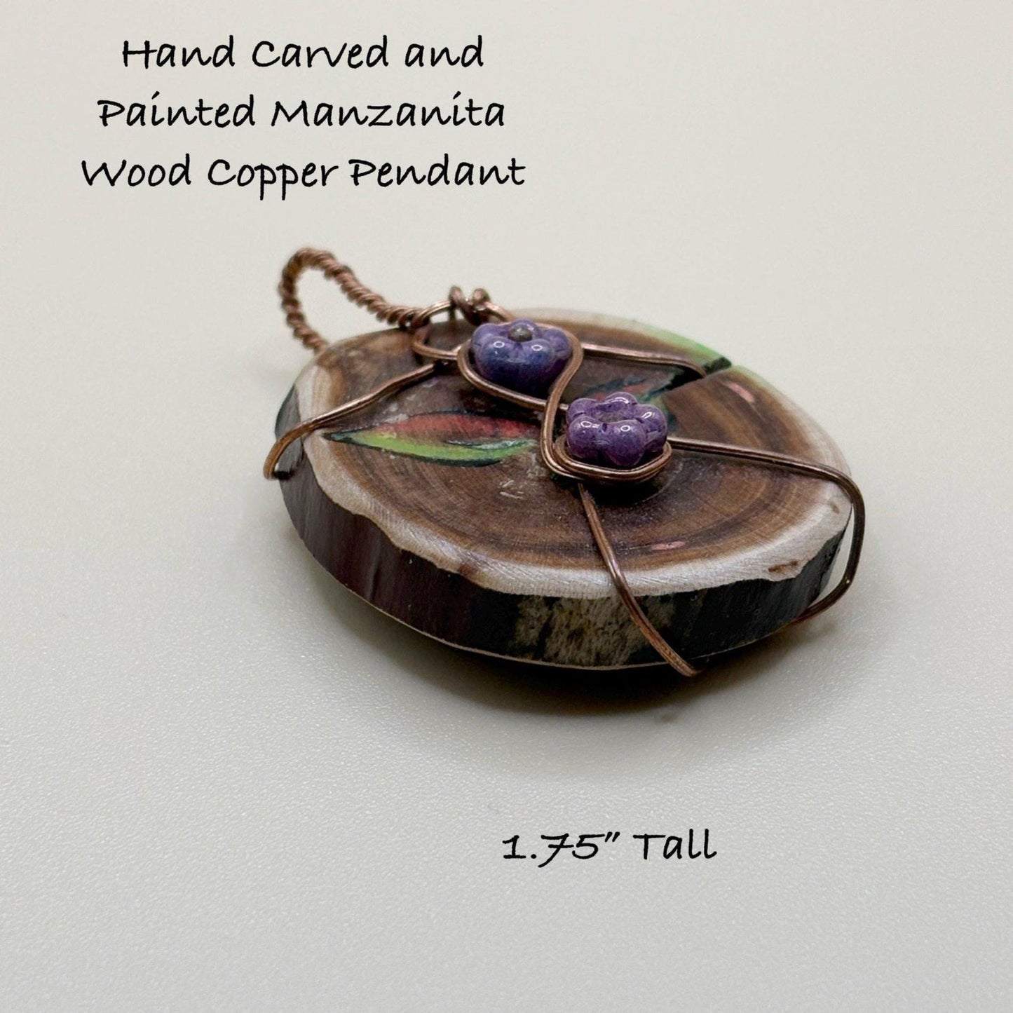 Hand carved and painted manzanita wood copper pendant with purple stones on a light gray background