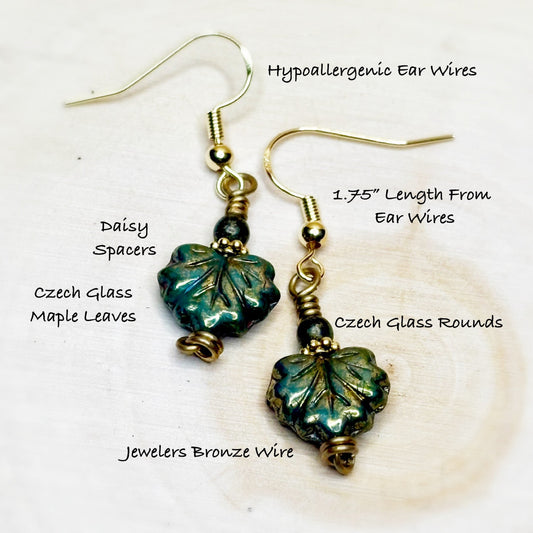 Pair of earrings with green leaf-shaped beads on a white background