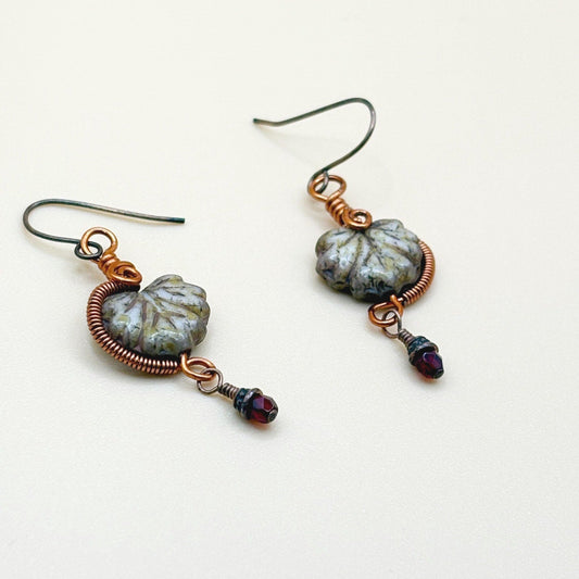 Pair of earrings with maple leaf glass beads and copper wirework on a white background-p