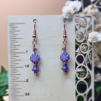 Purple floral earrings hanging on a display showing earring length