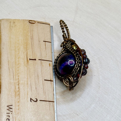 Jewelry pendant with a purple gemstone on a wooden block with measurement scale