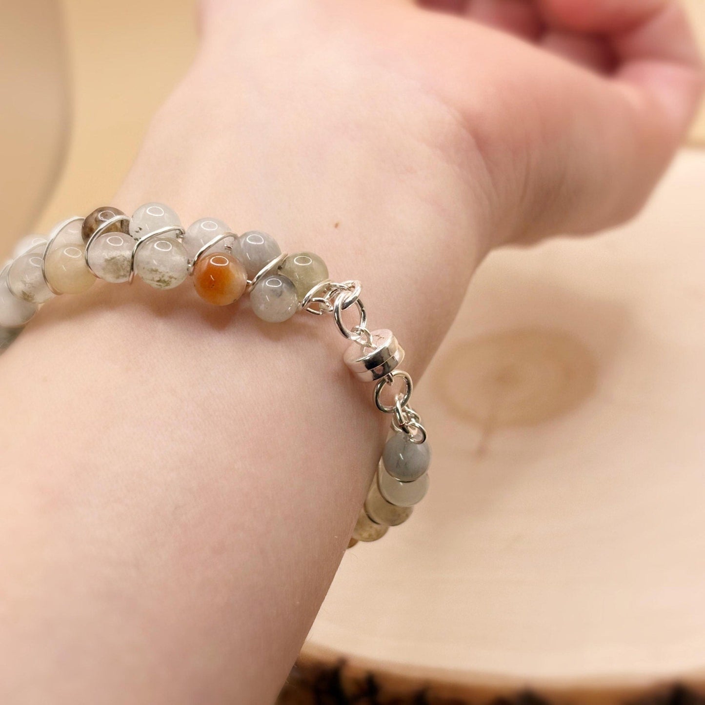 Beaded bracelet with a silver clasp on a wrist against a neutral background