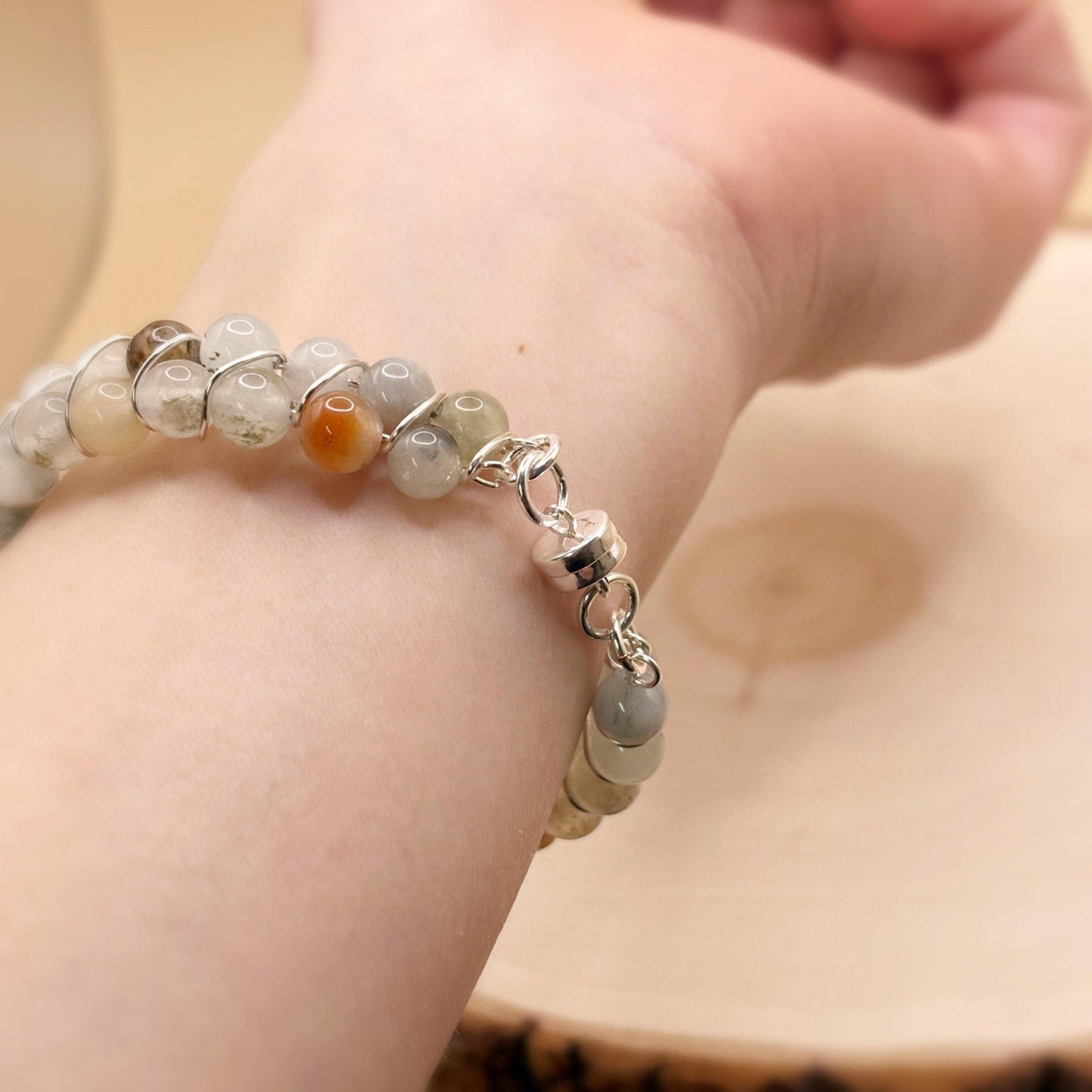 Beaded bracelet with a silver clasp on a wrist against a neutral background