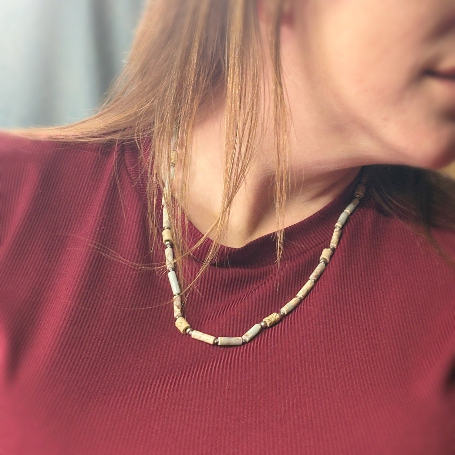 Close-up of a person wearing a beaded necklace with a blurred background