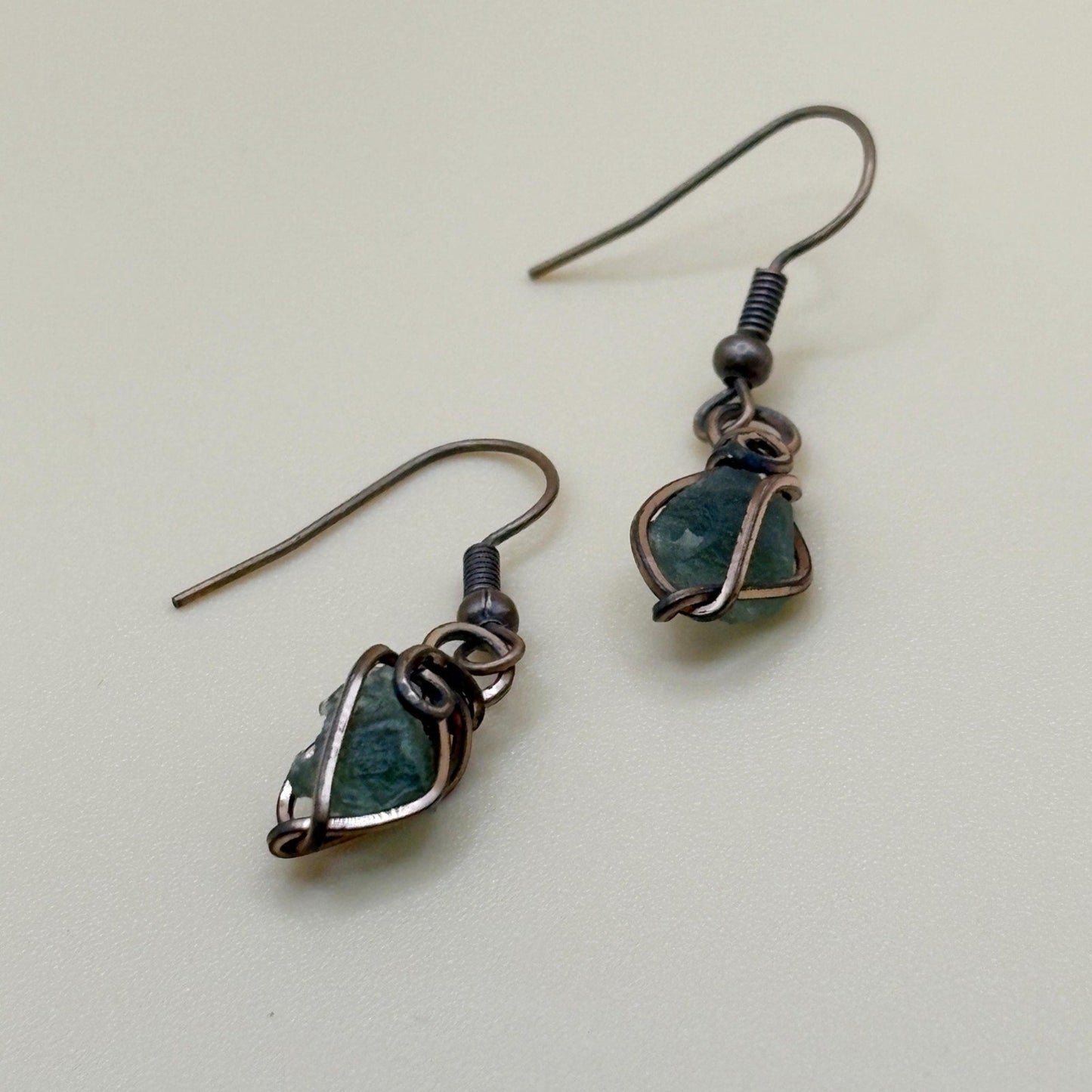 Pair of earrings with green gemstones on a light background