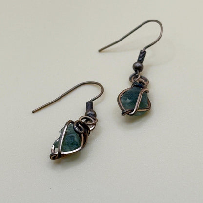 Pair of earrings with green gemstones on a light background