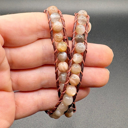 double leather beaded bracelet on a hand against a gray background