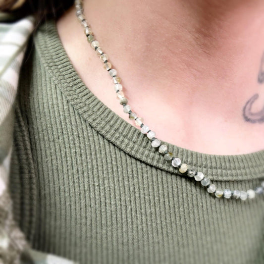 Necklace with small beads worn by a person in a green sweater-p