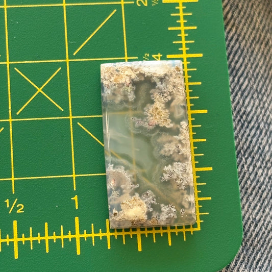 Rectangular piece of rock or mineral on a green cutting mat with yellow grid lines.