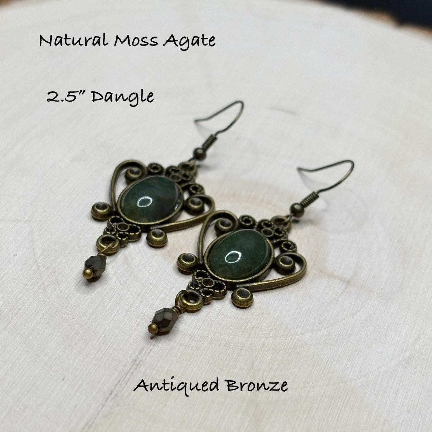 Antiqued bronze dangle earrings with natural moss agate stones on a light background