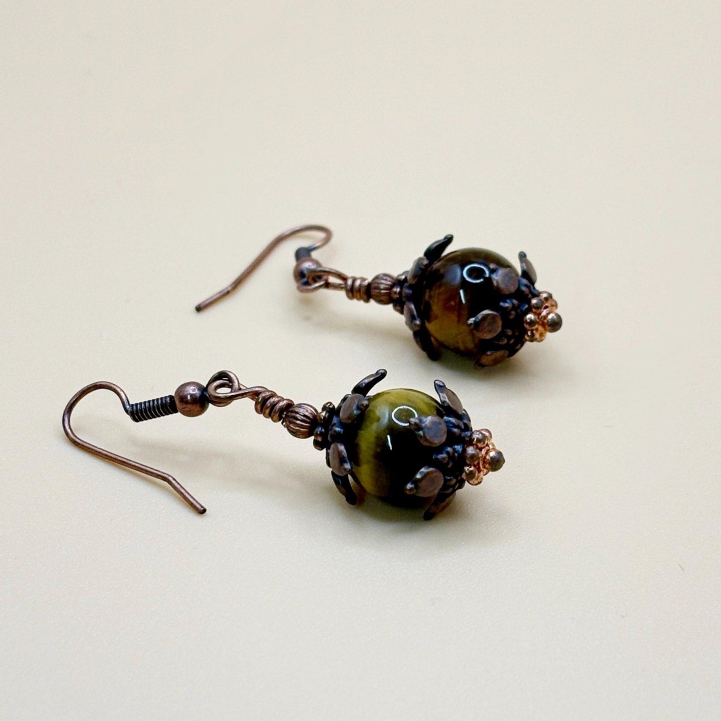 Pair of copper and brown beaded earrings on a beige background