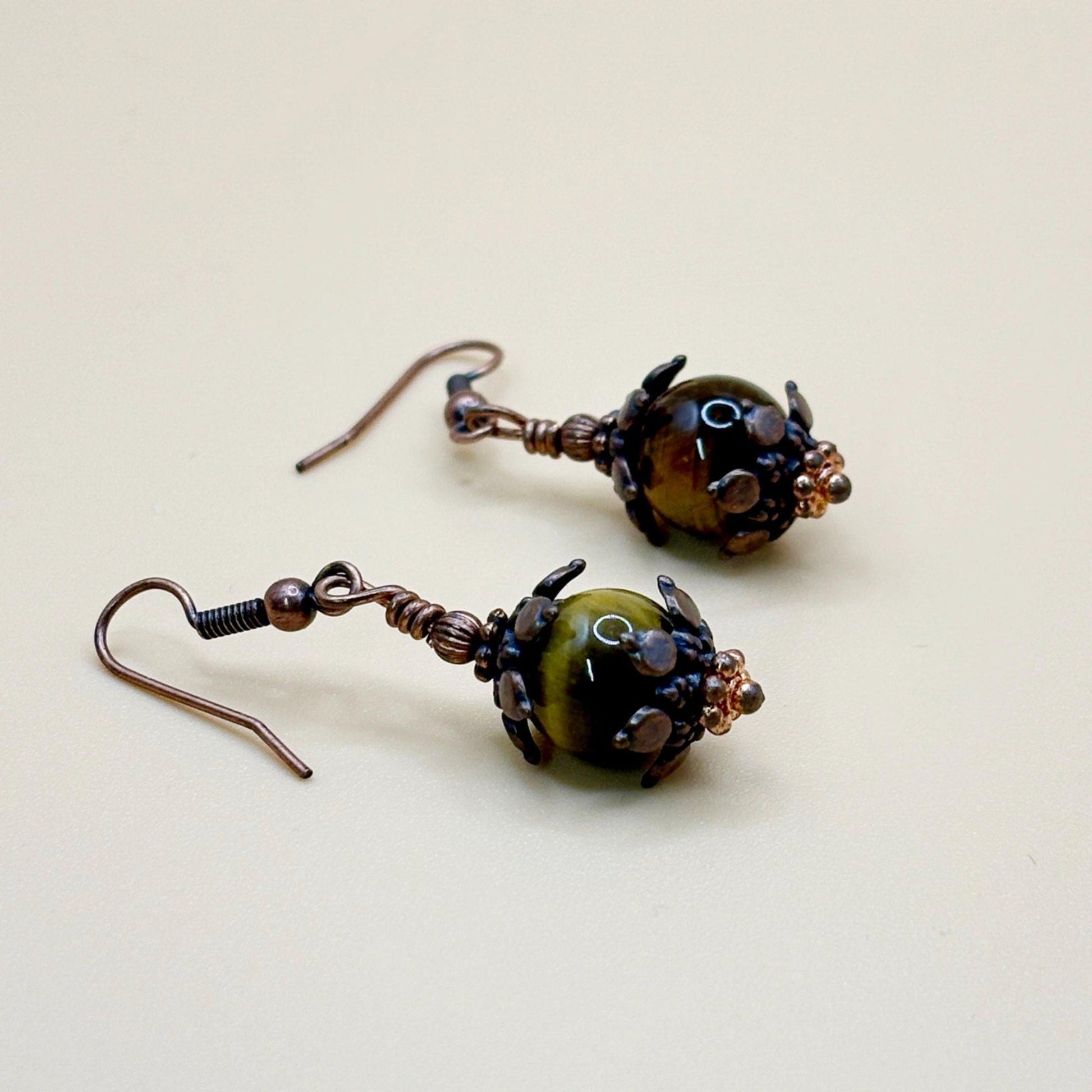 Pair of copper and brown beaded earrings on a beige background