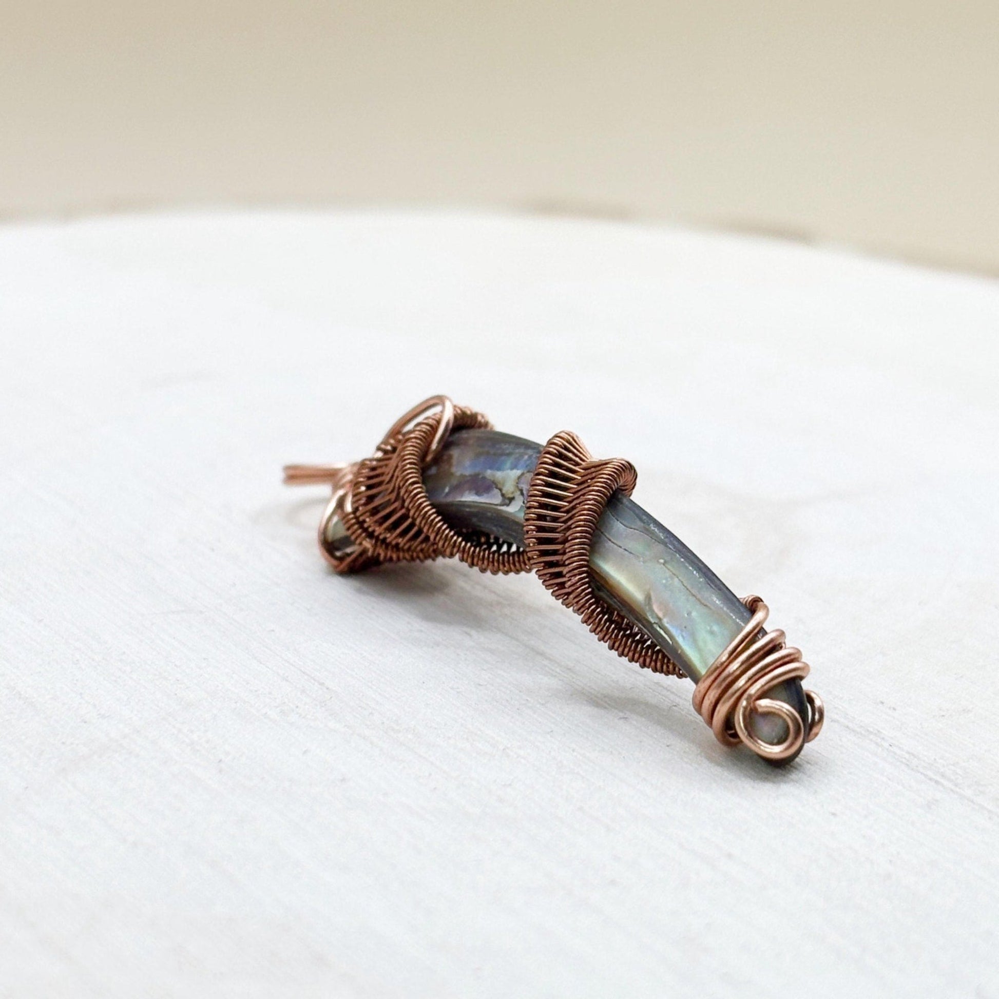 Jewelry pendant with copper wire wrapping on a white surface