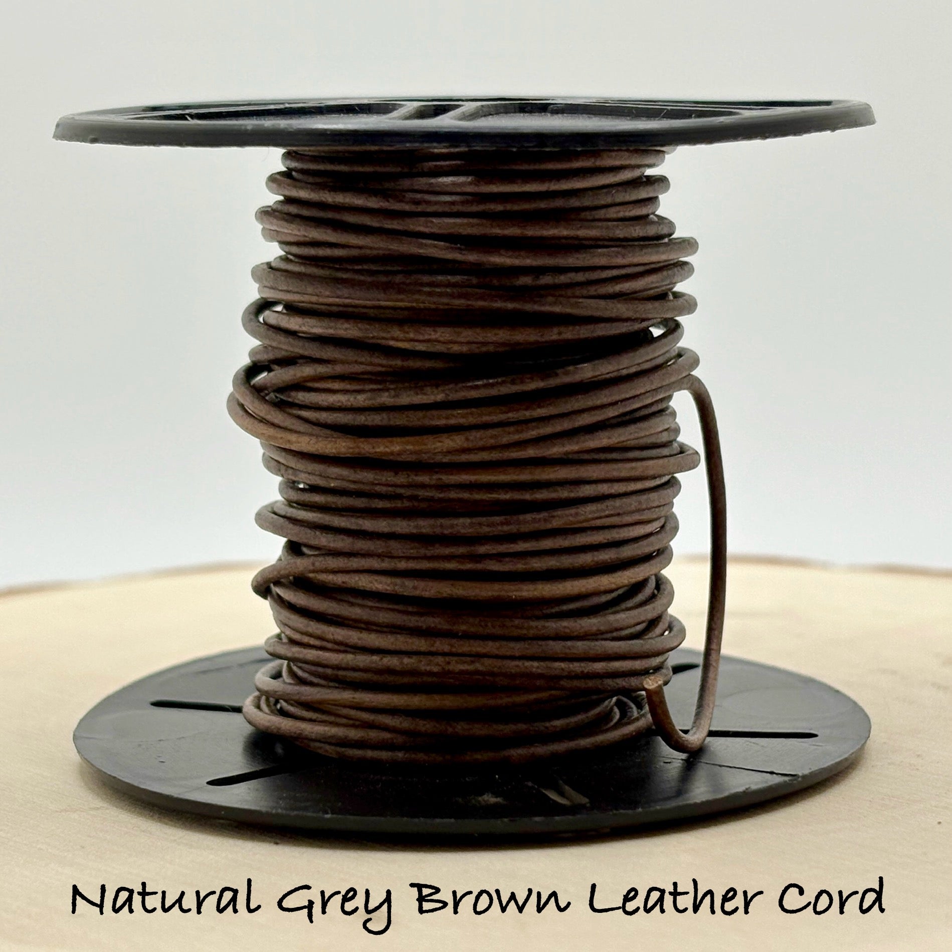 Spool of natural grey brown leather cord on a white background