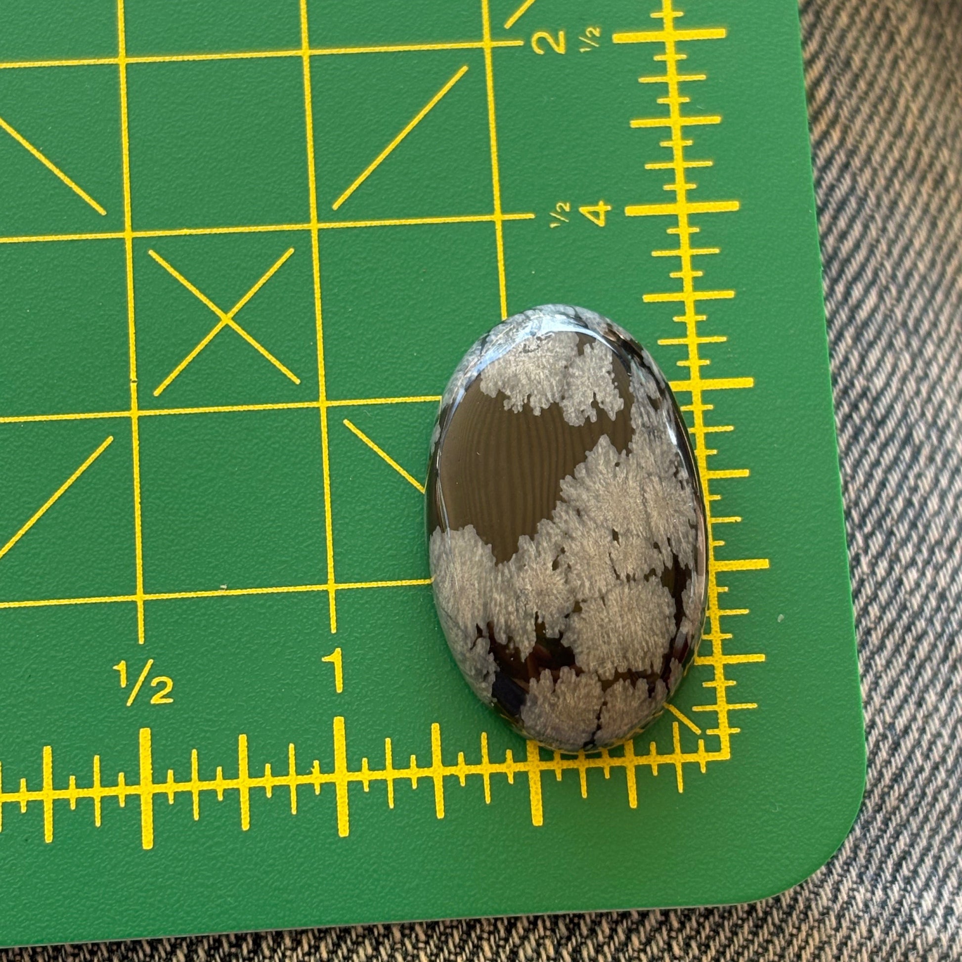 Oval-shaped stone on a green cutting mat with yellow measurements