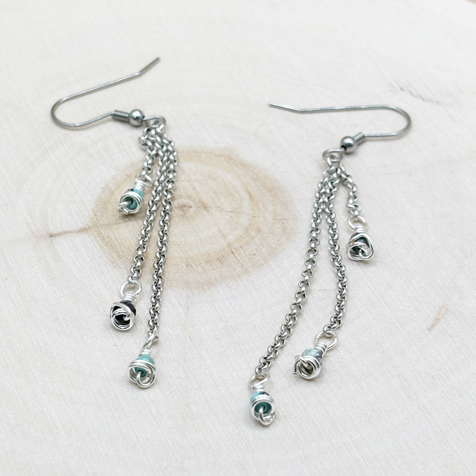 Pair of silver chain earrings with small circular charms on a light background
