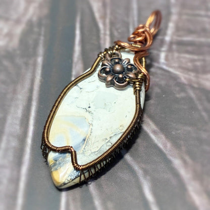 Elegant copper and bronze tone wire wrap sitting on a dark background 